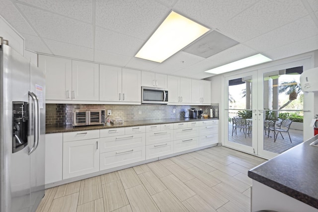 2880 NE 14th Street Cswy Unit 113, Pompano Beach, FL 33062 - kitchen with stainless steel appliances, a toaster, backsplash, a paneled ceiling, and dark countertops