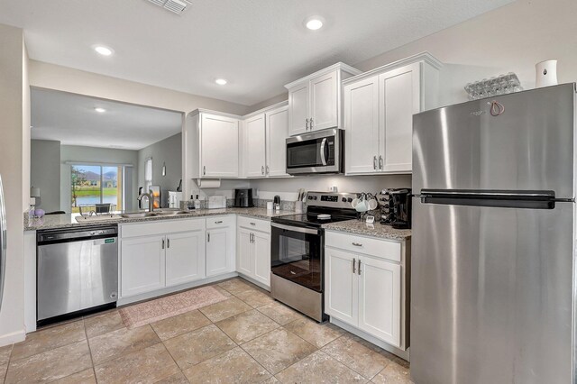 10771 SW Cremona Way, Port Saint Lucie, FL 34987 - kitchen featuring appliances with stainless steel finishes, a sink, white cabinets, light stone counters, and recessed lighting