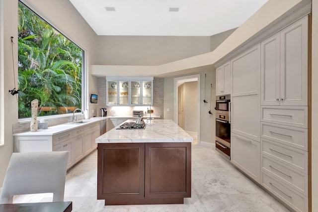 17652 Lake Estates Dr, Boca Raton, FL 33496 - kitchen featuring a sink, a warming drawer, stainless steel gas stovetop, glass insert cabinets, and light stone counters