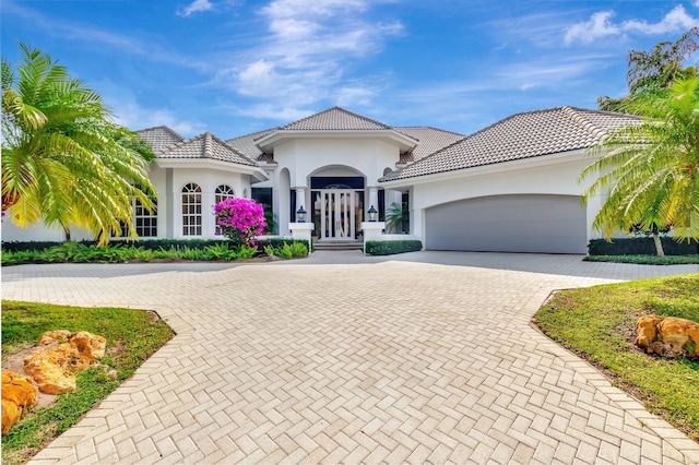 17652 Lake Estates Dr, Boca Raton, FL 33496 - mediterranean / spanish home featuring stucco siding, decorative driveway, a tiled roof, and a garage
