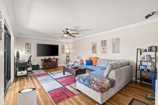 living area with a textured ceiling, a ceiling fan, crown molding, and wood finished floors