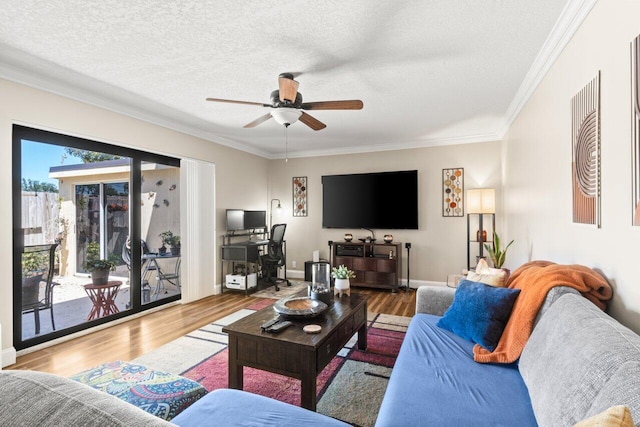 living area with ceiling fan, a textured ceiling, ornamental molding, wood finished floors, and baseboards