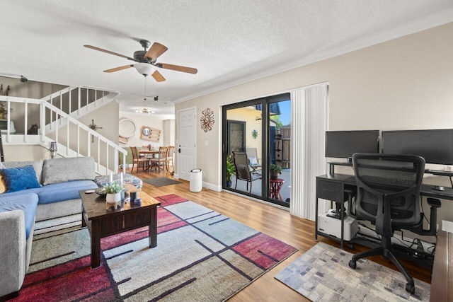 living room with crown molding, a textured ceiling, a ceiling fan, stairway, and wood finished floors
