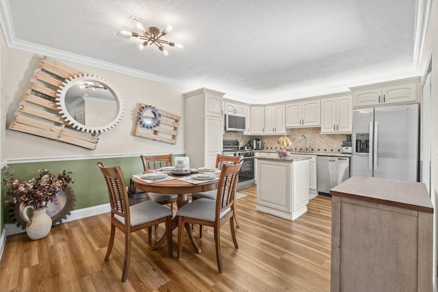 dining area featuring crown molding, light wood-style flooring, baseboards, and a textured ceiling