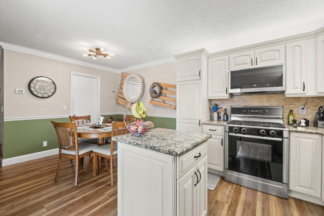 kitchen featuring light wood-style flooring, stainless steel microwave, a center island, and gas range