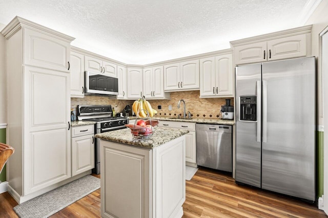 kitchen featuring stainless steel appliances, light wood finished floors, a textured ceiling, and a sink