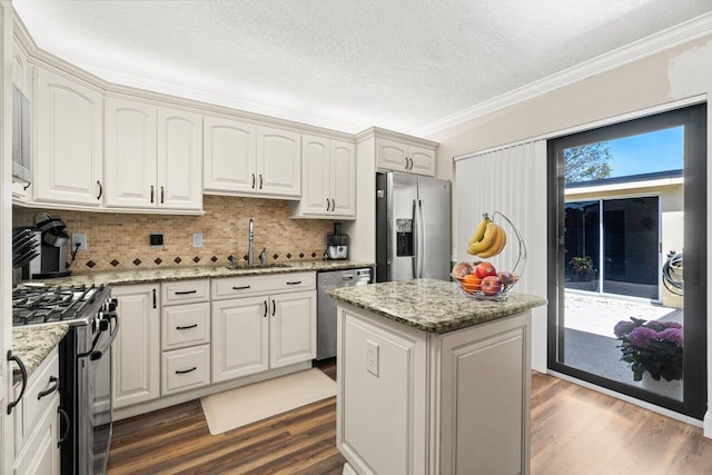 kitchen featuring dark wood finished floors, a sink, crown molding, and appliances with stainless steel finishes