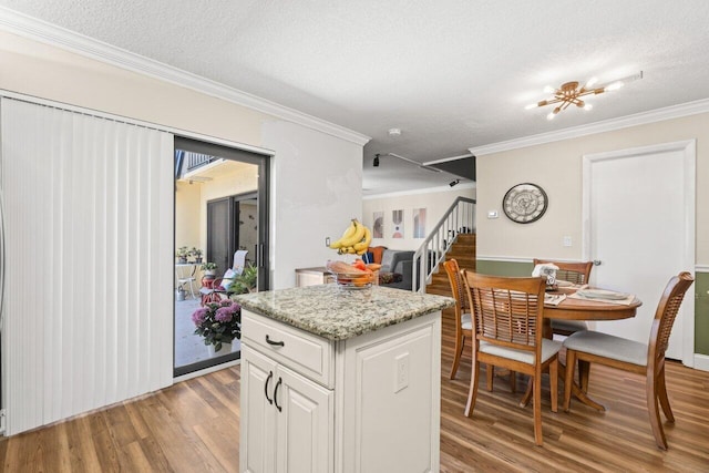 kitchen with crown molding, white cabinets, light wood finished floors, and a textured ceiling