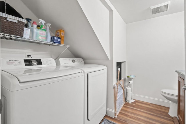 laundry area featuring laundry area, visible vents, wood finished floors, baseboards, and washing machine and dryer