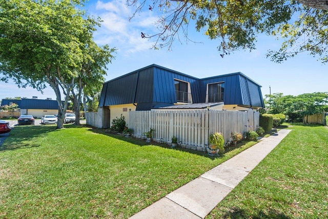 view of property exterior with fence, metal roof, and a lawn