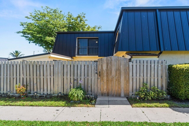 view of front of house with mansard roof, a fenced front yard, and stucco siding