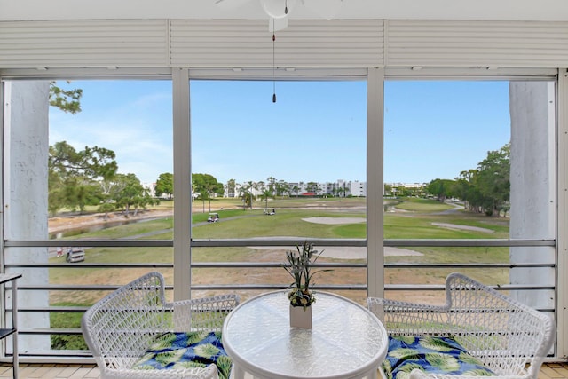 sunroom featuring golf course view, a wealth of natural light, and ceiling fan
