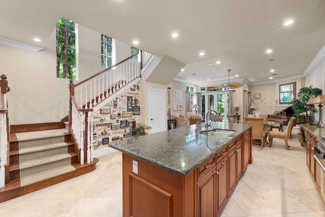kitchen with a sink, open floor plan, brown cabinets, crown molding, and an island with sink