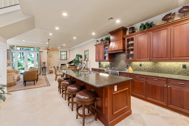 kitchen featuring a sink, tasteful backsplash, visible vents, custom range hood, and range