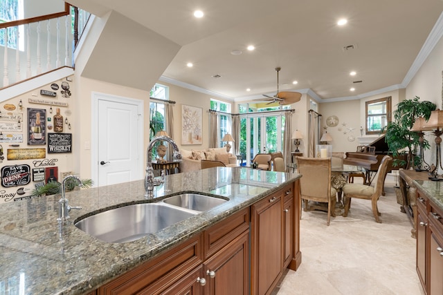 kitchen with brown cabinetry, open floor plan, a sink, and recessed lighting