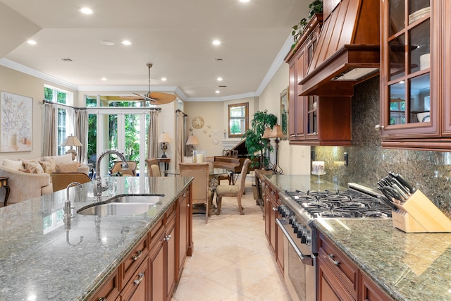 kitchen featuring decorative backsplash, open floor plan, a sink, and high end stove