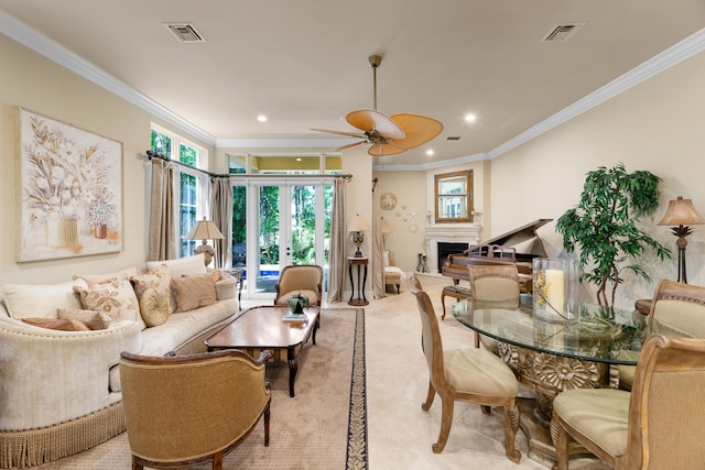 living room featuring a healthy amount of sunlight, visible vents, ceiling fan, a fireplace, and ornamental molding