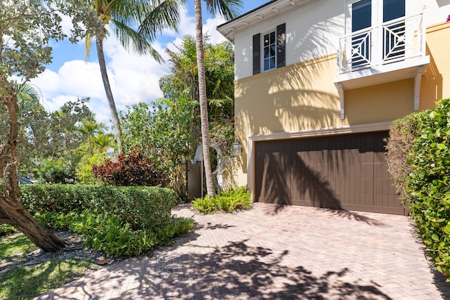 exterior space with an attached garage, decorative driveway, and stucco siding
