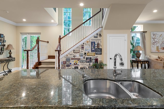 kitchen featuring recessed lighting, dark stone counters, ornamental molding, and a sink