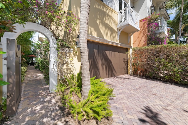 exterior space with stucco siding, decorative driveway, a balcony, and a garage
