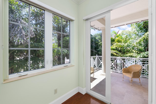 doorway to outside with crown molding, baseboards, and a healthy amount of sunlight