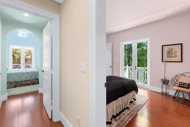 bedroom featuring arched walkways, baseboards, access to outside, and multiple windows