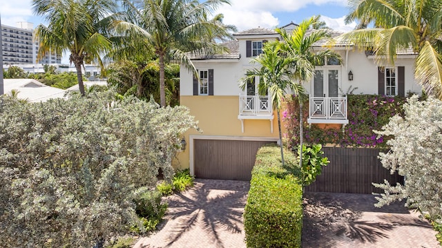 view of front of home with stucco siding, decorative driveway, a garage, and french doors