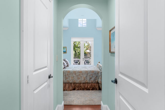 bedroom featuring arched walkways, access to outside, and wood finished floors