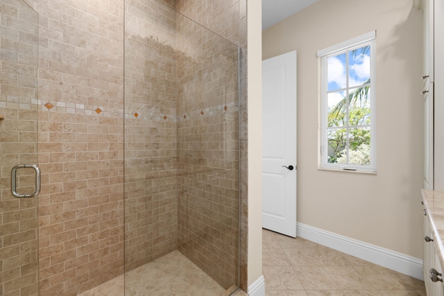 bathroom with a shower stall, a wealth of natural light, tile patterned flooring, and baseboards