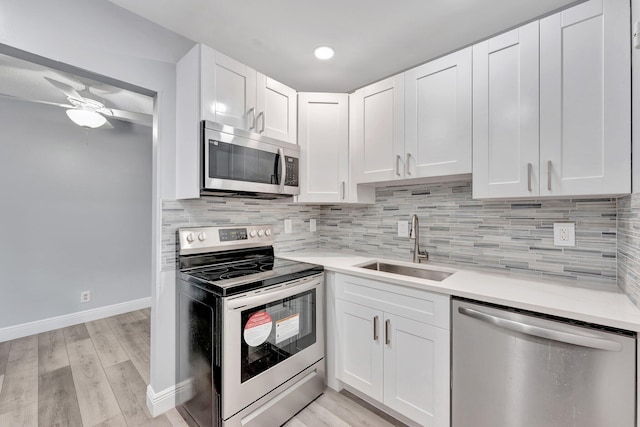 kitchen with ceiling fan, light countertops, a sink, stainless steel appliances, and baseboards