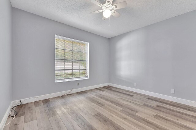 empty room with a ceiling fan, baseboards, light wood finished floors, and a textured ceiling