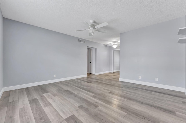 spare room with ceiling fan, a textured ceiling, visible vents, light wood finished floors, and baseboards