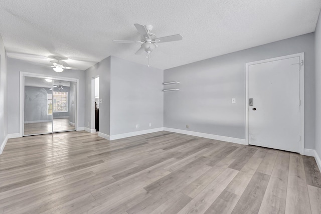 unfurnished living room featuring light wood-type flooring, a ceiling fan, baseboards, and a textured ceiling