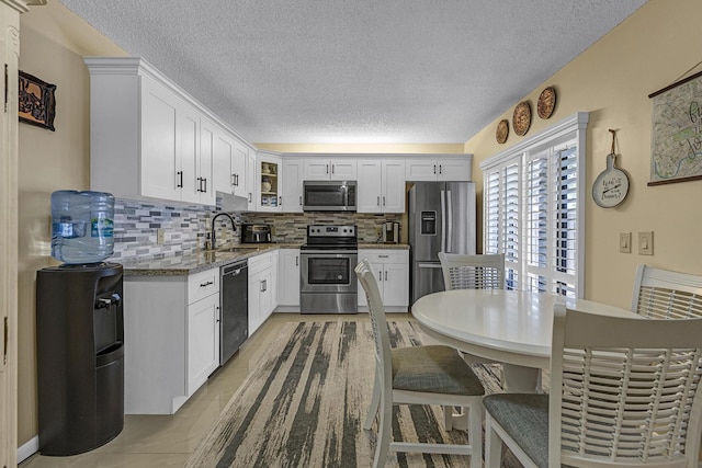 kitchen featuring stainless steel appliances, a textured ceiling, a sink, and tasteful backsplash