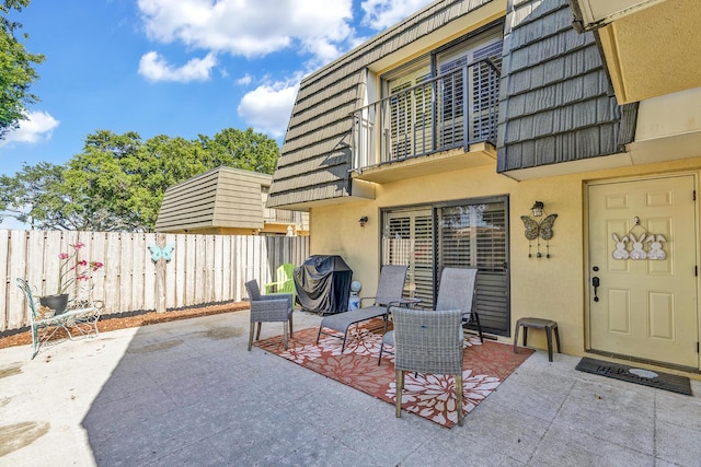 view of patio / terrace featuring fence and a balcony