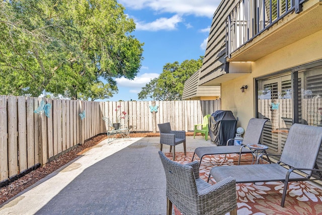 view of patio with a fenced backyard, grilling area, and a balcony
