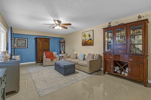 living room with baseboards, a ceiling fan, and a textured ceiling