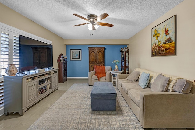 living room featuring baseboards, a ceiling fan, and a textured ceiling