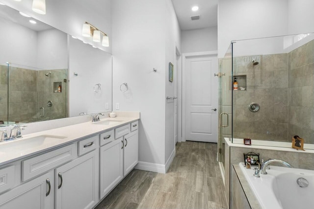 bathroom featuring a shower stall, wood finished floors, a sink, and visible vents