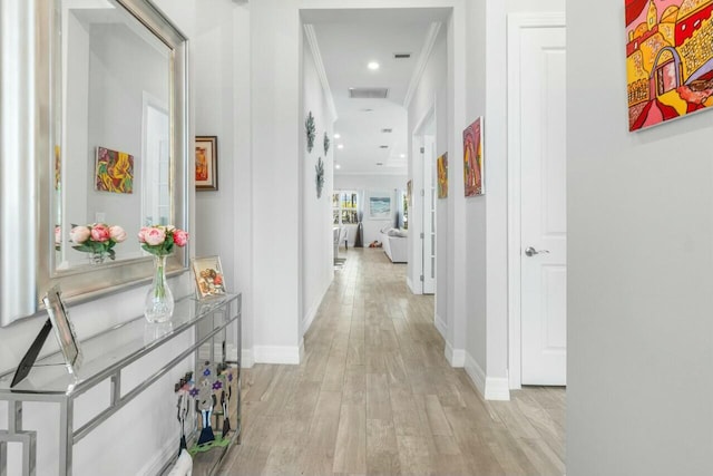 hallway with baseboards, visible vents, and light wood-style flooring