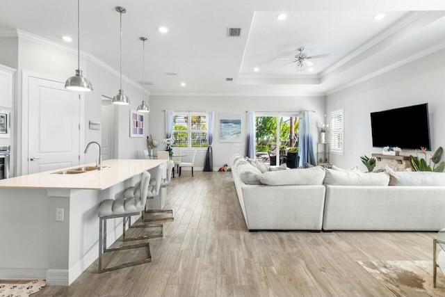 living room with ceiling fan, recessed lighting, ornamental molding, and light wood-type flooring
