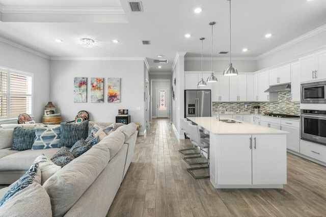 living area with recessed lighting, ornamental molding, visible vents, and light wood-type flooring