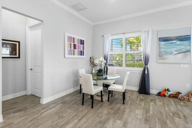 dining space featuring baseboards, crown molding, and wood finished floors