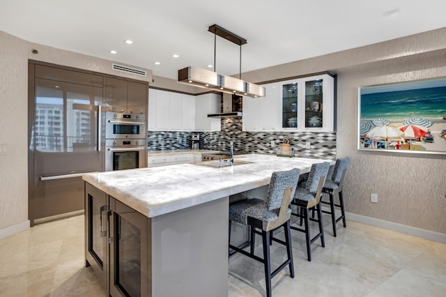 3740 S Ocean Blvd Unit 1205, Highland Beach, FL 33487 - kitchen featuring double oven, a kitchen breakfast bar, backsplash, glass insert cabinets, and white cabinetry