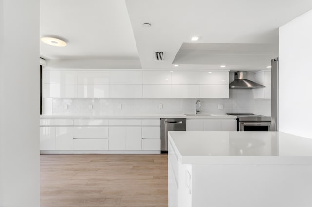 kitchen with visible vents, wall chimney range hood, stainless steel appliances, and modern cabinets