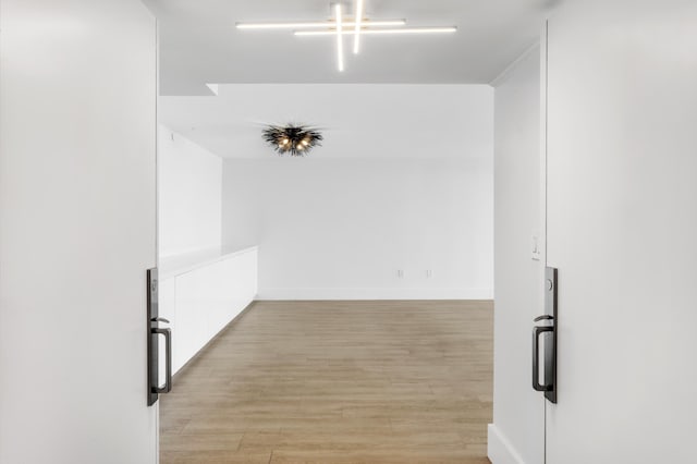 hall with light wood-type flooring and baseboards