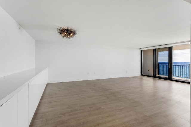 unfurnished room featuring expansive windows, baseboards, and light wood finished floors