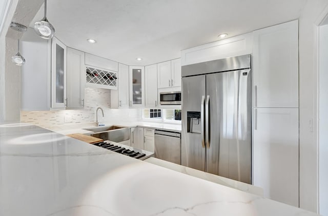 946 Paseo Morella, West Palm Beach, FL 33405 - kitchen with appliances with stainless steel finishes, a sink, white cabinetry, decorative backsplash, and glass insert cabinets