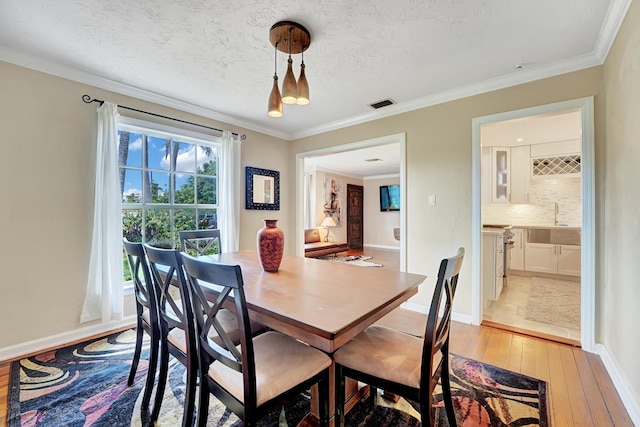 946 Paseo Morella, West Palm Beach, FL 33405 - dining room featuring light wood-style floors, crown molding, baseboards, and a textured ceiling