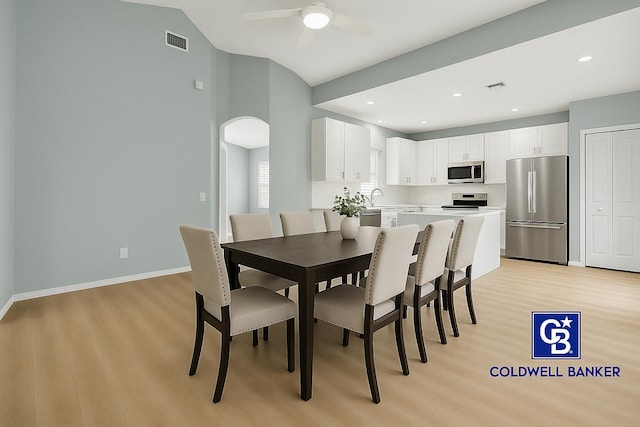 dining space with ceiling fan, arched walkways, baseboards, light wood-type flooring, and visible vents